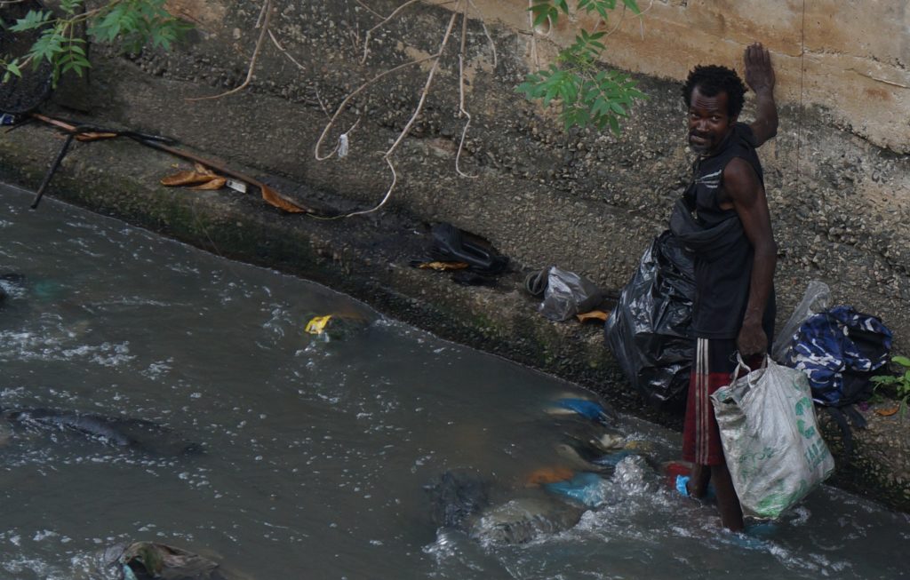 Homem procurando alimento em um valão — Foto Bruno Assunção (O Canal)